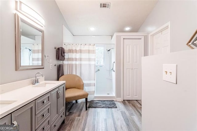 bathroom with wood-type flooring, a shower with curtain, vaulted ceiling, and vanity