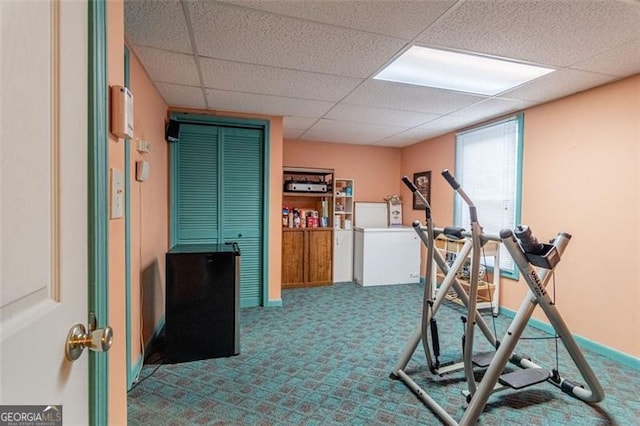 workout area with carpet floors and a paneled ceiling