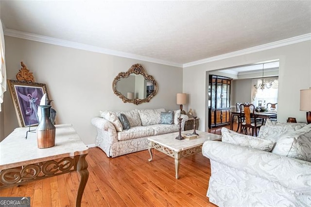 living room featuring ornamental molding, a notable chandelier, and light hardwood / wood-style floors