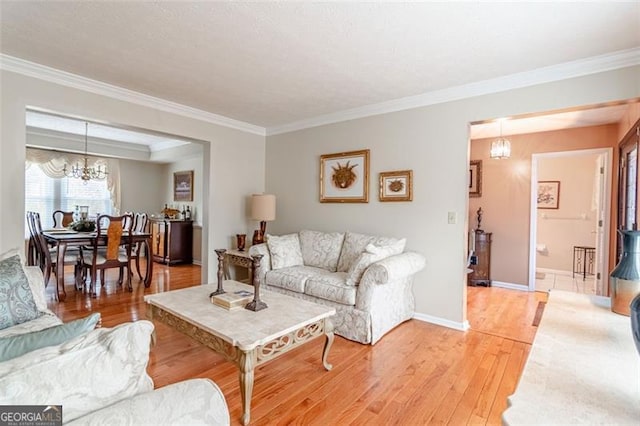 living room with an inviting chandelier, hardwood / wood-style floors, and crown molding