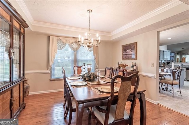 dining space with a raised ceiling, hardwood / wood-style floors, and crown molding