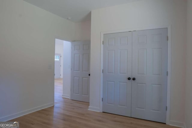 unfurnished bedroom with light wood-type flooring and a closet