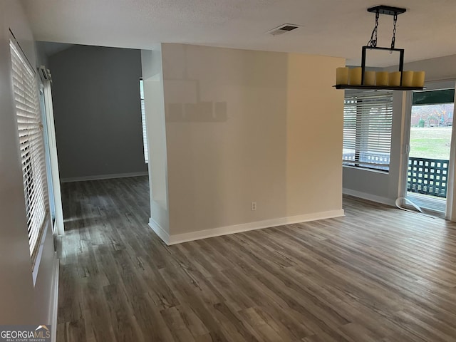 empty room featuring a textured ceiling and dark hardwood / wood-style floors