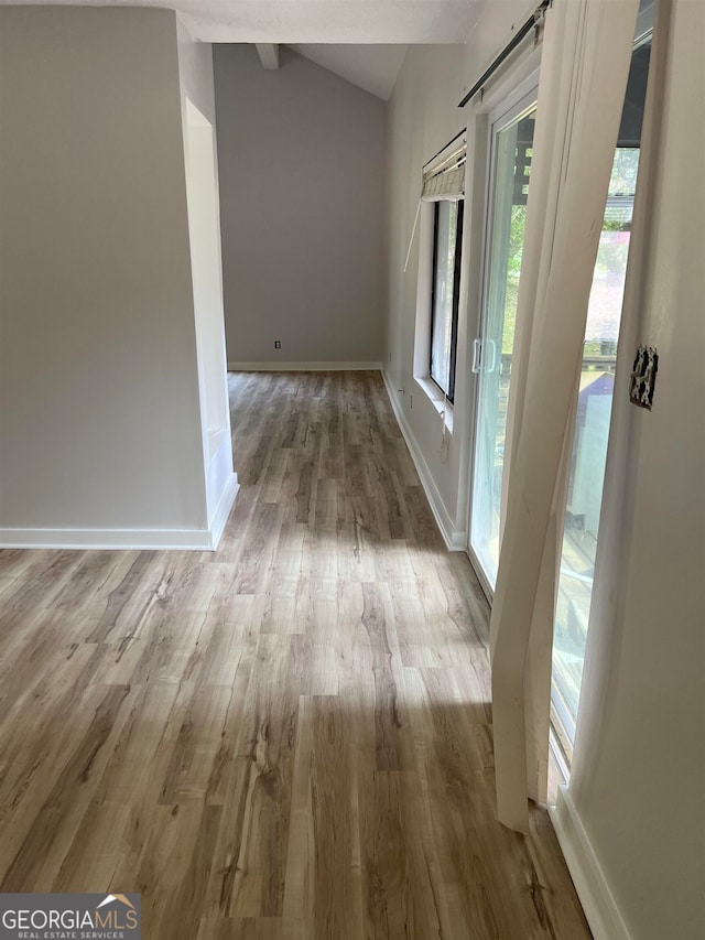 hall featuring vaulted ceiling and light hardwood / wood-style flooring