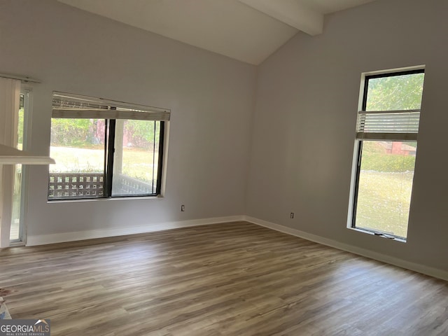 unfurnished room featuring vaulted ceiling with beams and hardwood / wood-style floors