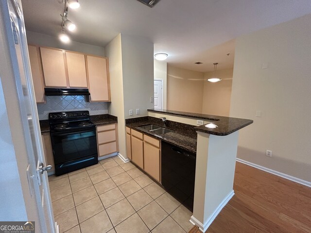 kitchen with sink, kitchen peninsula, decorative light fixtures, black appliances, and dark stone counters