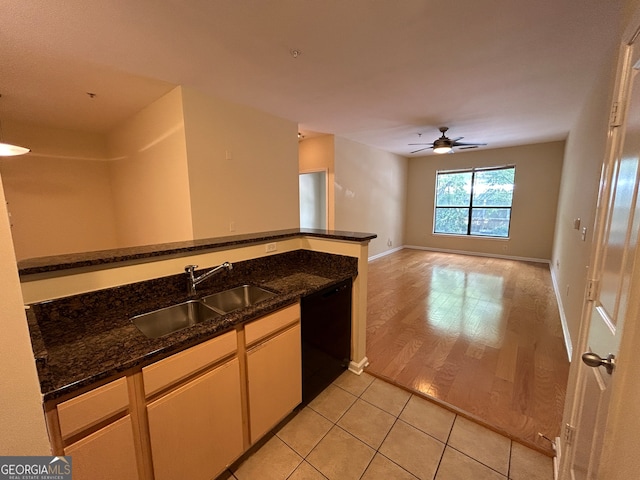 kitchen featuring dark stone countertops, black dishwasher, ceiling fan, light hardwood / wood-style flooring, and sink