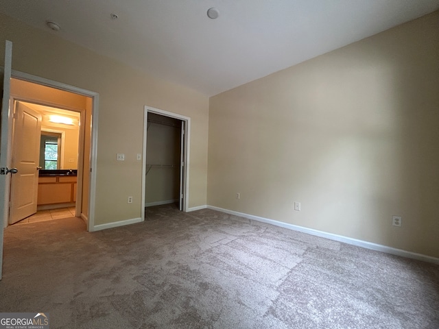 unfurnished bedroom with light carpet, a closet, and a walk in closet