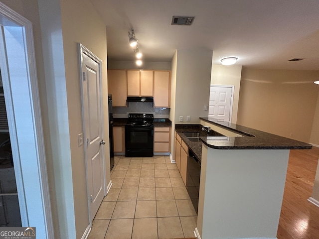 kitchen with kitchen peninsula, backsplash, dark stone counters, black appliances, and light wood-type flooring