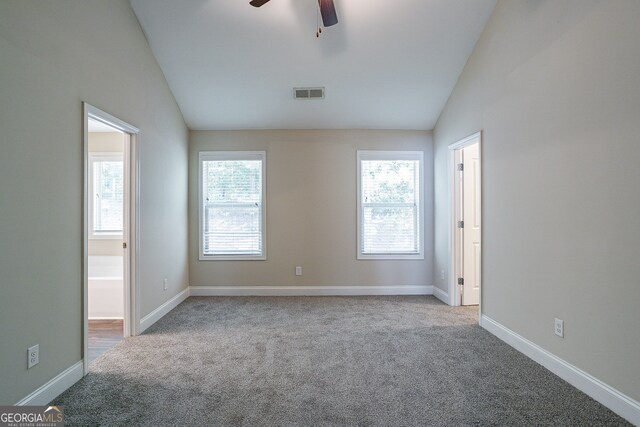 empty room featuring ceiling fan, light colored carpet, plenty of natural light, and vaulted ceiling