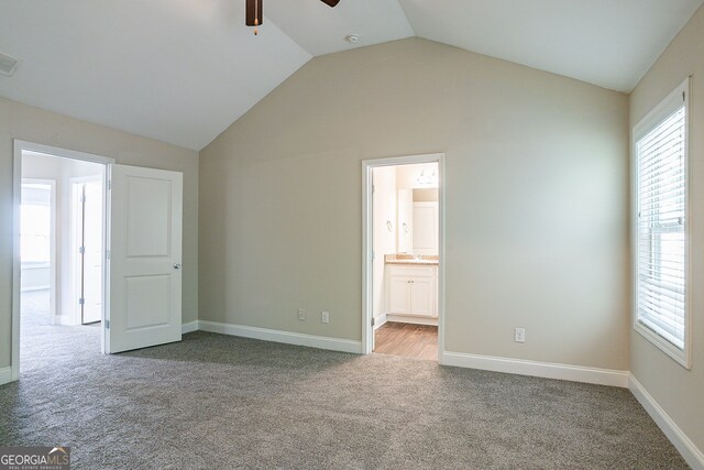 unfurnished bedroom with multiple windows, light carpet, ensuite bath, and ceiling fan