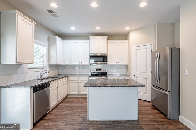 kitchen featuring dark wood-type flooring, white cabinetry, a kitchen island, stainless steel appliances, and dark stone countertops