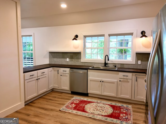 kitchen with decorative backsplash, sink, stainless steel appliances, and white cabinets