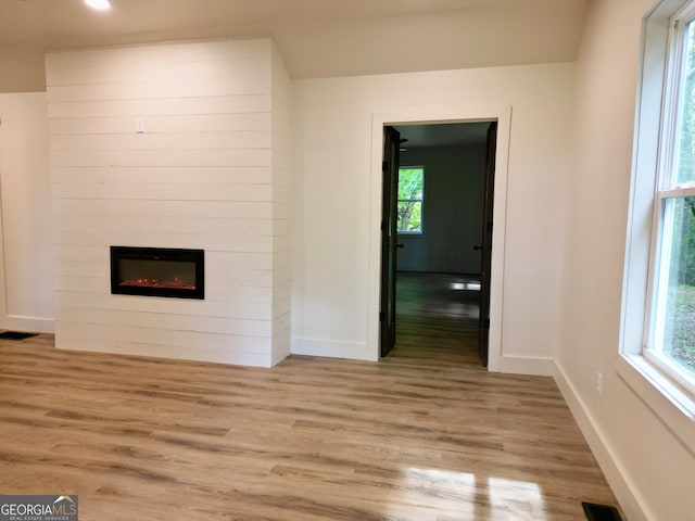 unfurnished living room featuring a large fireplace, light hardwood / wood-style flooring, and a wealth of natural light