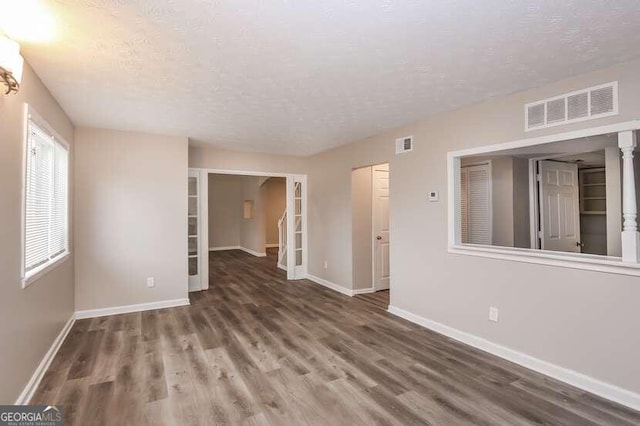 empty room featuring a textured ceiling and dark hardwood / wood-style flooring