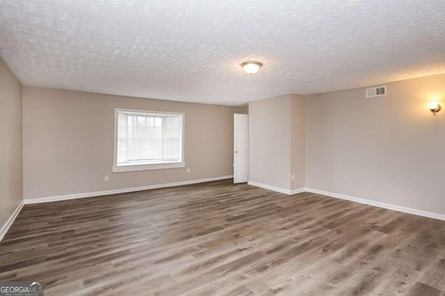 empty room featuring a textured ceiling and dark hardwood / wood-style flooring