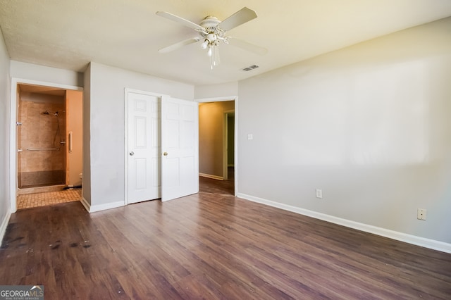 unfurnished bedroom featuring dark hardwood / wood-style floors, ensuite bathroom, and ceiling fan