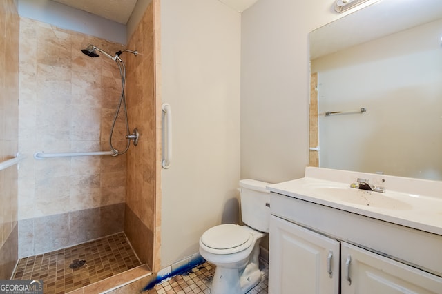 bathroom with vanity, a tile shower, toilet, and tile patterned flooring