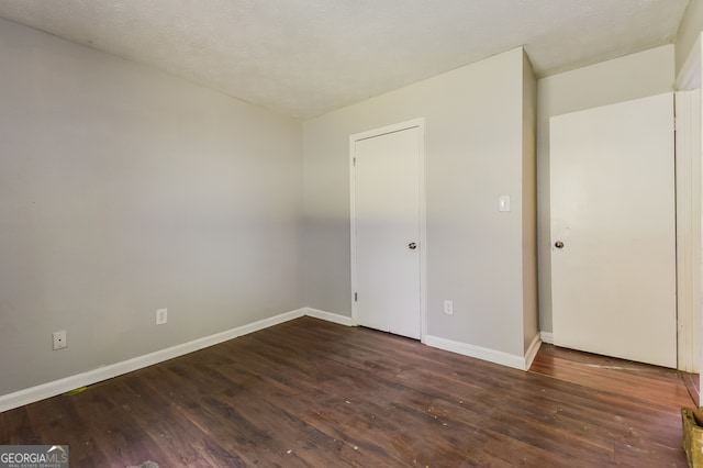 empty room featuring a textured ceiling and dark hardwood / wood-style flooring