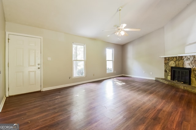 unfurnished living room featuring a stone fireplace, dark wood-type flooring, and ceiling fan