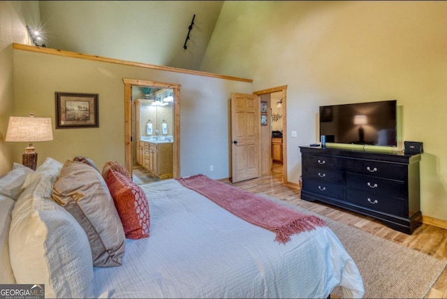 bedroom featuring ensuite bath, light hardwood / wood-style flooring, and high vaulted ceiling