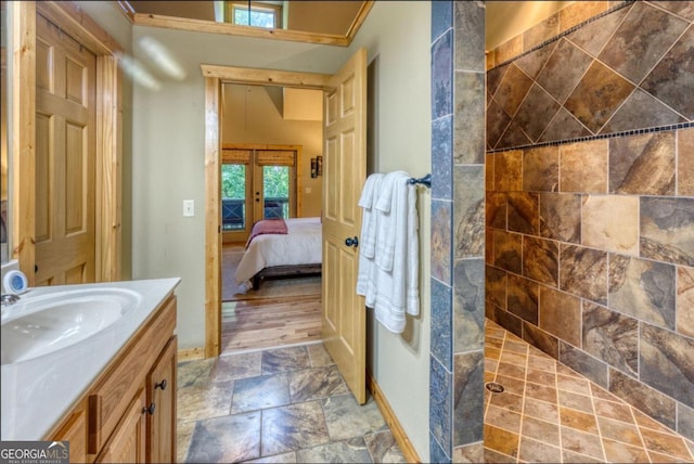 bathroom featuring wood-type flooring, vanity, french doors, and a tile shower