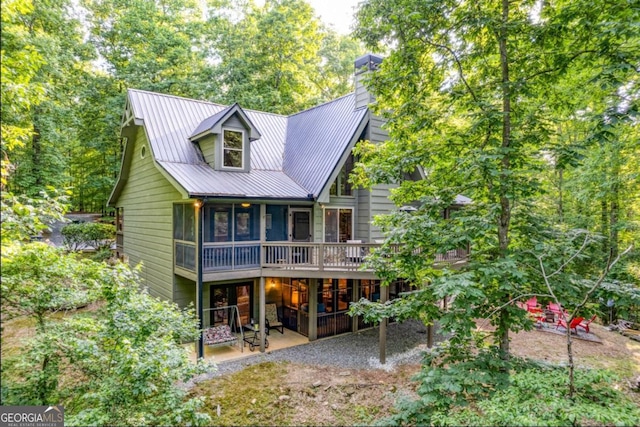 rear view of house with a wooden deck and a patio