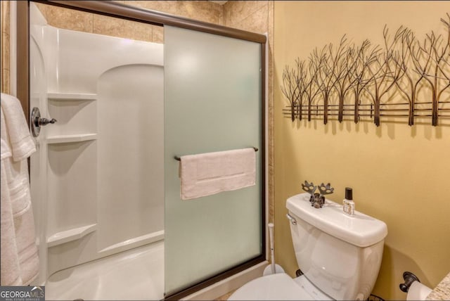 bathroom featuring toilet and a shower with door