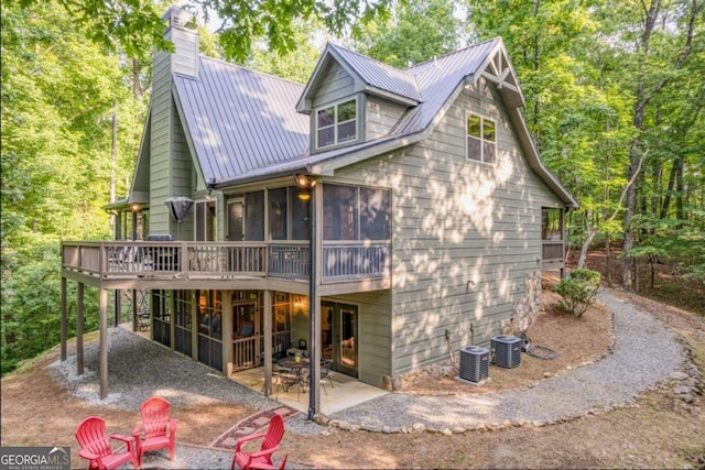 back of property with cooling unit, a deck, a sunroom, and a patio area