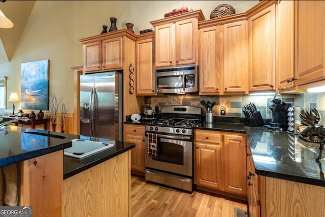 kitchen with light hardwood / wood-style flooring, stainless steel appliances, lofted ceiling, and decorative backsplash