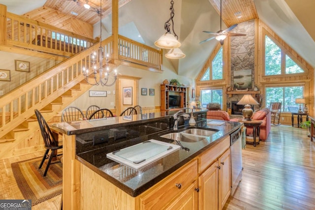 kitchen featuring sink, ceiling fan with notable chandelier, a fireplace, high vaulted ceiling, and light brown cabinetry