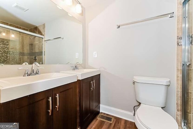 bathroom featuring hardwood / wood-style floors, vanity, toilet, and an enclosed shower