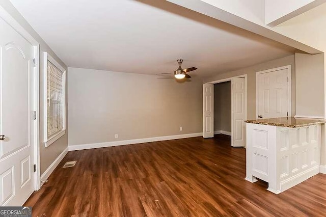 unfurnished living room with ceiling fan and dark wood-type flooring