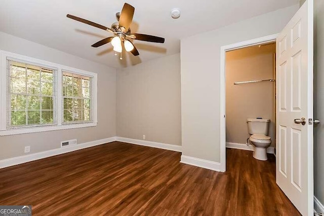 unfurnished bedroom featuring ceiling fan, a closet, dark hardwood / wood-style floors, a spacious closet, and ensuite bath