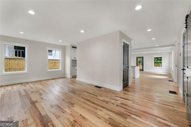 spare room featuring light hardwood / wood-style floors, a barn door, and a wealth of natural light