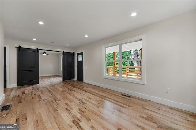 interior space with a barn door and light hardwood / wood-style floors