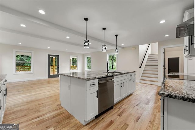 kitchen with a center island with sink, hanging light fixtures, a healthy amount of sunlight, and stainless steel dishwasher