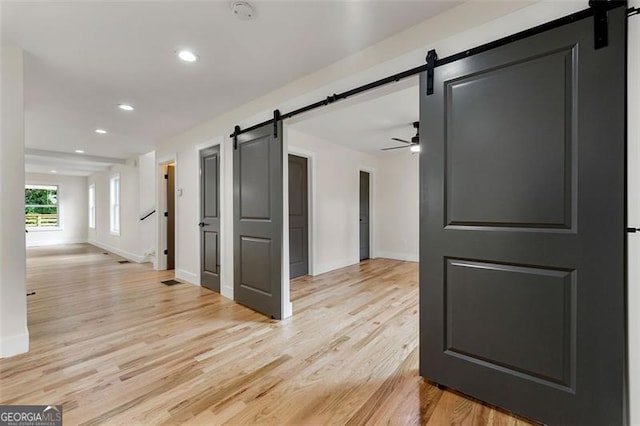 hall with a barn door and light hardwood / wood-style flooring