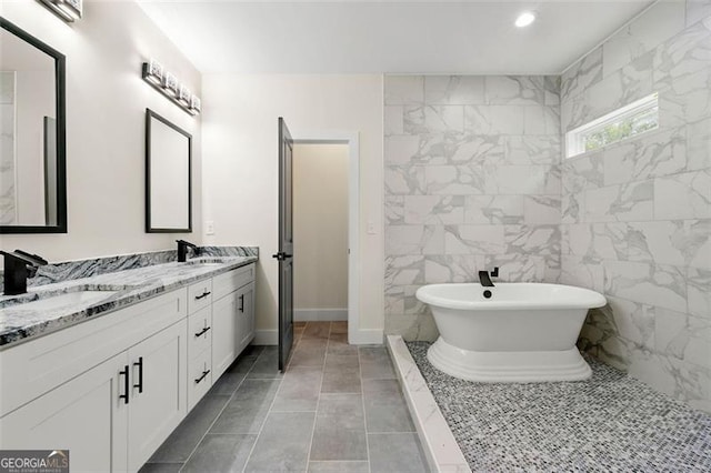 bathroom with vanity, tile walls, a washtub, and tile patterned floors