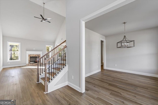 interior space featuring dark wood-style floors, stairway, a brick fireplace, and a healthy amount of sunlight