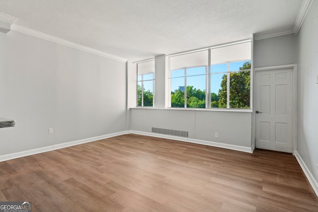 spare room featuring light wood-type flooring, crown molding, and a textured ceiling