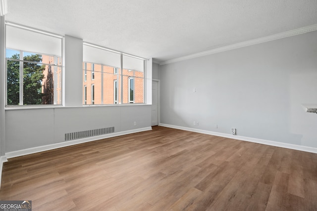 spare room with hardwood / wood-style flooring, crown molding, and a textured ceiling