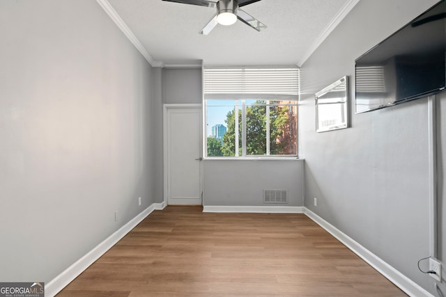 unfurnished room featuring a textured ceiling, light hardwood / wood-style floors, ceiling fan, and crown molding