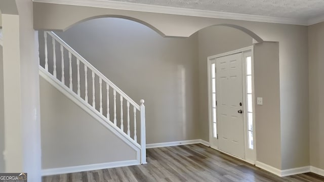 entrance foyer with hardwood / wood-style flooring, ornamental molding, and a textured ceiling