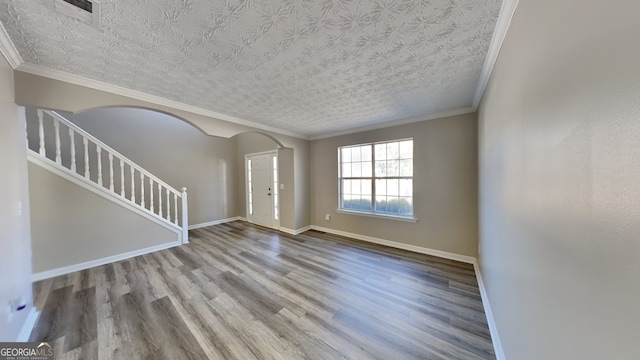 empty room with a textured ceiling, light hardwood / wood-style flooring, and crown molding