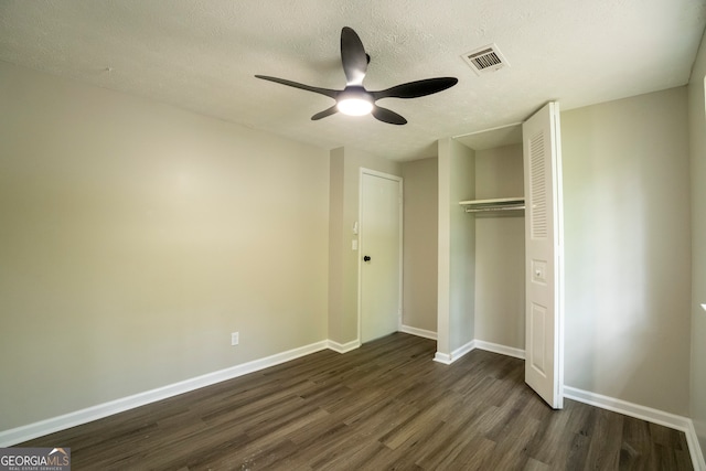 unfurnished bedroom featuring a closet, dark hardwood / wood-style floors, a textured ceiling, and ceiling fan