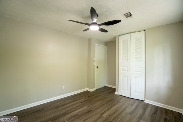 unfurnished bedroom featuring a closet, ceiling fan, a textured ceiling, and dark hardwood / wood-style flooring