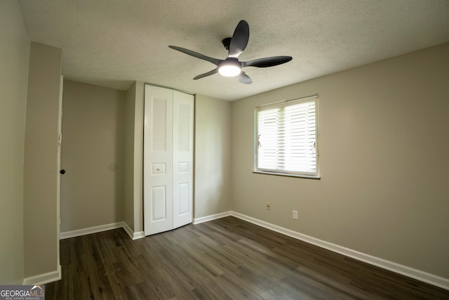 unfurnished bedroom featuring dark wood-type flooring, ceiling fan, a closet, and a textured ceiling