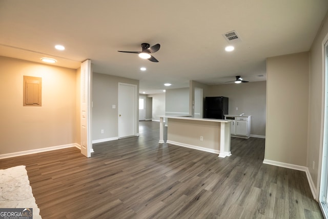 unfurnished living room featuring dark wood-type flooring, ceiling fan, and electric panel