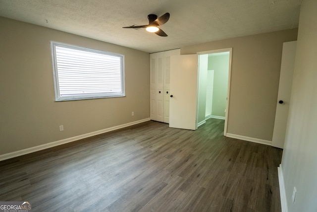 unfurnished bedroom with a closet, a textured ceiling, dark wood-type flooring, and ceiling fan